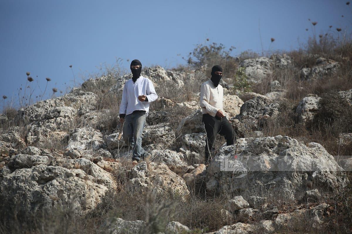 مستعمرون خلال مهاجمتهم للمشاركين في فعالية لقطف الزيتون في بلدة بيتا جنوب نابلس (وفا)